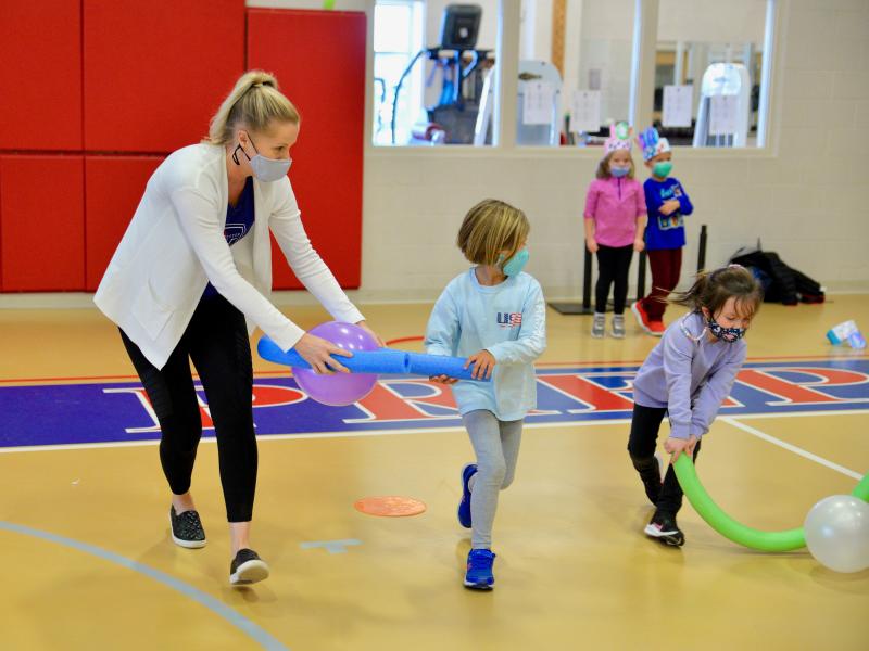 Dressed in athletic wear, kindergarteners participated in 100 Ways to Move games and activities. Racing to the line are (l-r) teacher Heather Dennis, Margot Hidell and Emery Anthony.